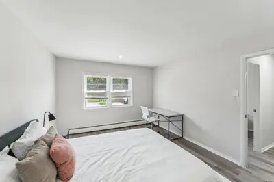a white bedroom with a bed and a desk at Pine Brook 1111 I State of the art 15 Bd Apt in Newark