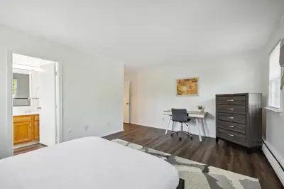 a white bedroom with a bed and a desk at Pine Brook 1122 I Pool Gym I Free Parking ! in Newark