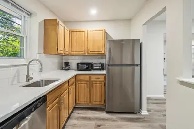a kitchen with wooden cabinets and a stainless steel refrigerator at Pine Brook 118 I Modern Corporate 2bd I Parking in Newark