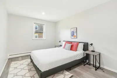 a white bedroom with a large bed with red pillows at Pine Brook 1218 I Cozy & comfy I Free Parking in Newark