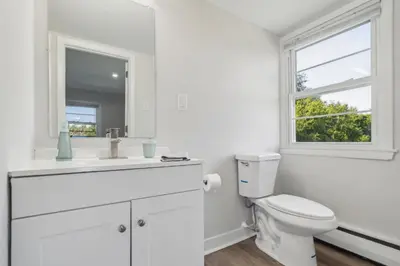 a white bathroom with a toilet and a window at Pine Brook 124 I Modern Gem I Free Parking in Newark