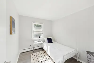 a white bedroom with a bed and a window at Pine Brook 509 I Corporate 15Br Apt I Parking in Newark