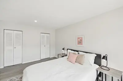 a white bedroom with a white bed and two lamps at Pine Brook 509 I Corporate 15Br Apt I Parking in Newark