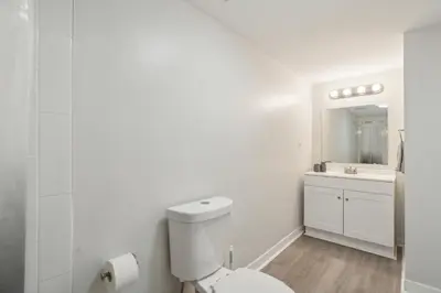 a white bathroom with a toilet and a sink at Pine Brook 808 I Your Newark Retreat I Pool & Gym in Newark