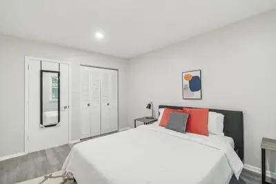 a white bedroom with a large bed with red pillows at Pine Brook 808 I Your Newark Retreat I Pool & Gym in Newark