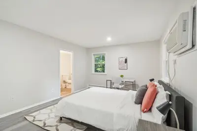 a white bedroom with a large bed with orange pillows at Pine Brook 808 I Your Newark Retreat I Pool & Gym in Newark