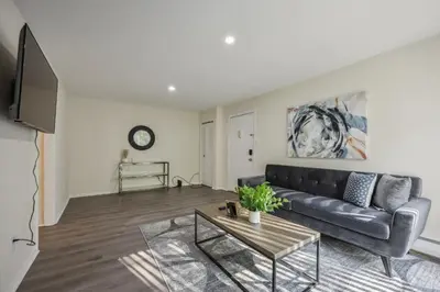 a living room with a black couch and a table at Pine Brook 816 I Corporate 2Br Apartment ! in Newark