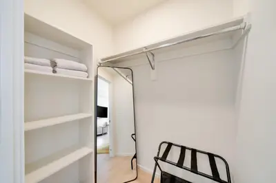 a walk in closet with a mirror and a chair at One Grove in Jersey City in Jersey City