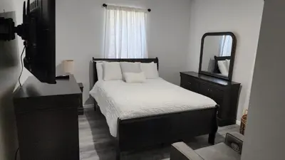 a bedroom with a bed with a mirror and a dresser at Comfortable Apartment in Irvington