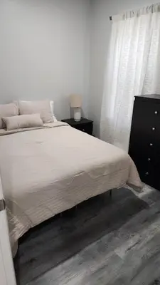 a bedroom with a bed and a dresser and a window at Comfortable Apartment in Irvington