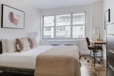 a bedroom with a bed and a desk and a window at Blueground Murray Hill gym lounge wd NYC-1565 in New York