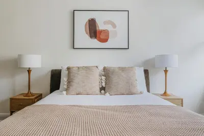 a bedroom with a bed with two lamps and a picture at Blueground Murray Hill gym lounge wd NYC-1565 in New York