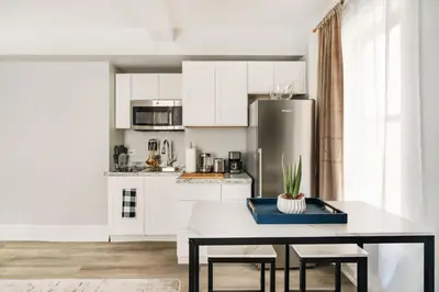 a kitchen with white cabinets and a table with chairs at 73-308 New 1BR 1Bth UWS Doorman Gym in New York