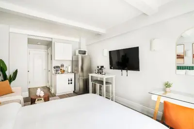 a white room with a bed and a kitchen at 73-518 Newly Reno Studio UWS Doorman Gym Laundry in New York