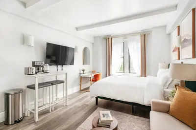 a white bedroom with a bed and a tv at 73-518 Newly Reno Studio UWS Doorman Gym Laundry in New York