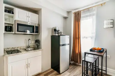 a kitchen with a black refrigerator and a table at 73-608 New 1BR 1Bth UWS Doorman Gym in New York
