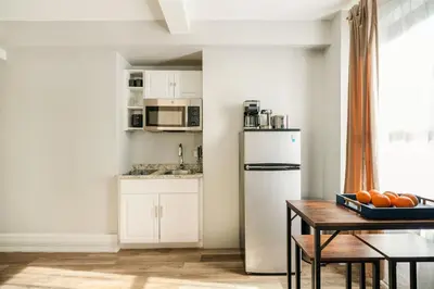 a kitchen with a table and a white refrigerator at 73-608 New 1BR 1Bth UWS Doorman Gym in New York