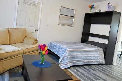 a living room with a bed and a vase of flowers on a table at Cozy Sanctuary in Jersey City