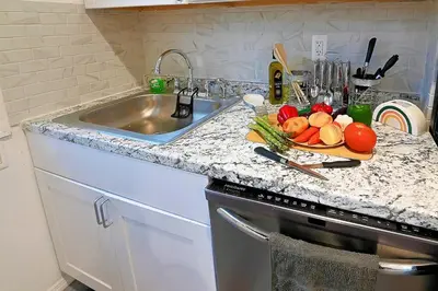 a kitchen counter with a plate of vegetables on a cutting board at Hidden Gem-1Bedroom with Plenty Free Street Parking in Communipaw