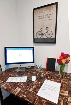 a desk with a computer monitor and a keyboard and flowers at Hidden Gem-1Bedroom with Plenty Free Street Parking in Communipaw