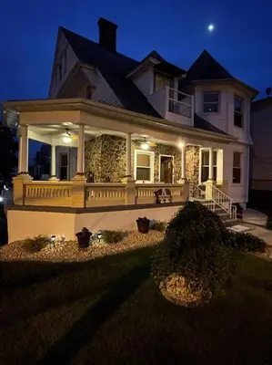a large white house with a porch at night at Lovely Victorian Home with Bed and Breakfast Energy in West Bergen