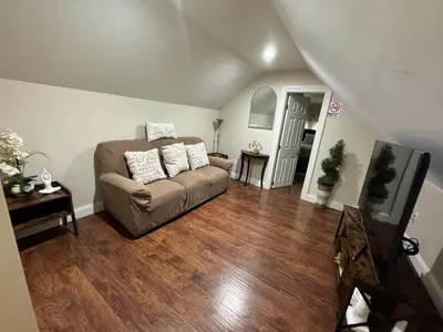 a living room with a couch and wooden floors at Private Cozy Apartment - Only 5 min Away from Newark Airport and 30 min to NYC in Elizabeth