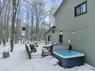 a house with a hot tub in the snow at La Casita at Creekview in Gouldsboro