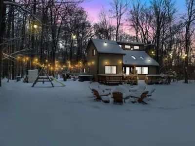 a house in the snow at night with lights at La Casita at Creekview in Gouldsboro
