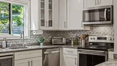a kitchen with white cabinets and stainless steel appliances at Slopeside Escape by AvantStay Walk to Ski Lifts Arcade Games Shuffleboard in Tannersville
