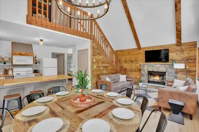 a dining room with a table and a fireplace at Chalet Lake, Movie Theater, Hot Tub, Arcade in Gouldsboro