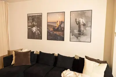 a living room with a couch and four pictures on the wall at Paloma - Lux Industrial Townhome in Newark