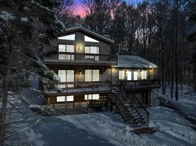 a house in the woods with snow on the ground at Winter Hideaway - Sled Hill, Hot Tub, Fireplace, Game Room in Gouldsboro