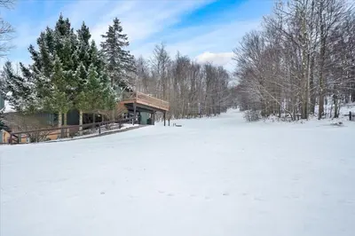 a snow covered field with a building in the distance at Winter Hideaway - Sled Hill, Hot Tub, Fireplace, Game Room in Gouldsboro