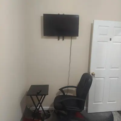 a room with a chair and a television on a wall at Deluxe Room E in Jersey City