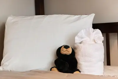 a teddy bear sitting on a bed next to a pillow at Love Lace Retreat in Albrightsville