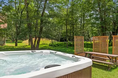 a hot tub in a yard next to a bench at Love Lace Retreat in Albrightsville