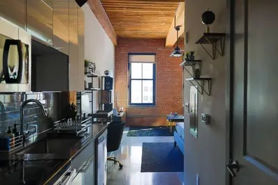 a kitchen with a sink and a living room at The Othello - Luxury Industrial Loft near NYC in Communipaw