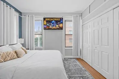 a white bedroom with a bed and a window at Hoboken 15 Min Train to Manhattan Full Kitchen in Hoboken