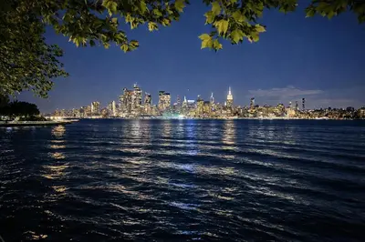a view of the city from the water at night at Hoboken 15 Min Train to Manhattan Full Kitchen in Hoboken