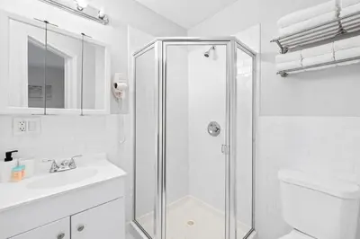 a white bathroom with a shower and a sink at Hoboken 15 Min Train to Manhattan Full Kitchen in Hoboken