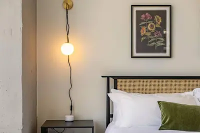 a bedroom with a bed and a lamp on a table at Modern Loft 15 Min from NYC with City View & Pool in Croxton