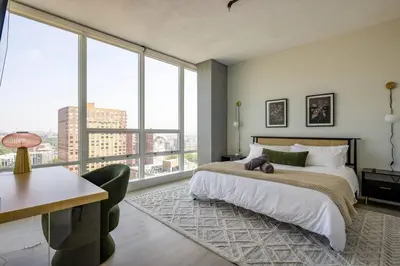 a bedroom with a bed and a desk and windows at Modern Loft 15 Min from NYC with City View & Pool in Croxton