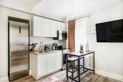 a kitchen with white cabinets and a stainless steel refrigerator at 73-508 New 1BR 1Bth UWS Doorman Gym in New York