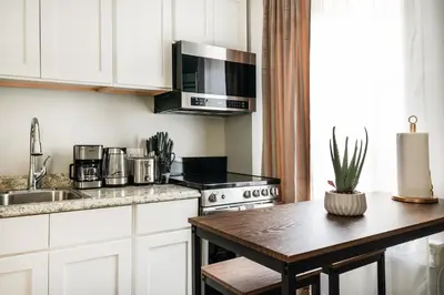 a kitchen with white cabinets and a wooden table at 73-508 New 1BR 1Bth UWS Doorman Gym in New York