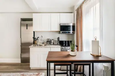 a kitchen with white cabinets and a wooden table at 73-508 New 1BR 1Bth UWS Doorman Gym in New York