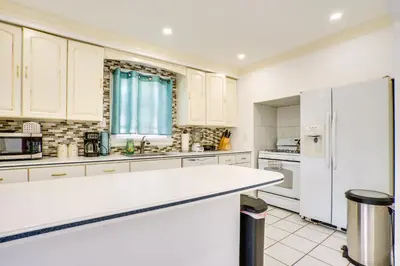a kitchen with white cabinets and a white refrigerator at 4 Mi to NYC, Shared Yard Englewood Apartment! in Englewood