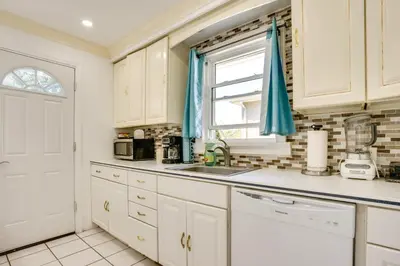a kitchen with white cabinets and a sink and a window at 4 Mi to NYC, Shared Yard Englewood Apartment! in Englewood