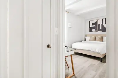 a white bedroom with a bed and a desk at 73-1406 New 1BR 1Bth UWS Doorman Gym in New York