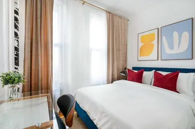 a bedroom with a bed with red pillows and a glass table at 444-1A Beautiful 1BR Midtown West in New York