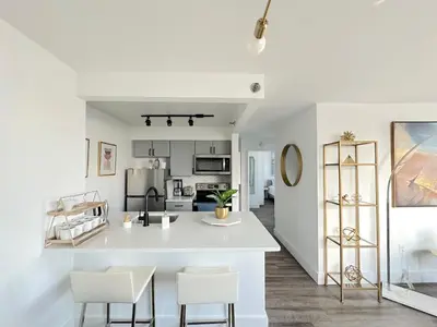 a white kitchen with white chairs and a counter at Luxury 2BR - Elevator-Gym-Laundry-10 Min to NYC in Hoboken